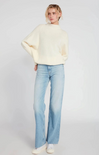 Person wearing a cream sweater and light blue jeans on a white background
