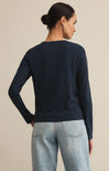 Person wearing a navy sweater and light blue jeans on a beige background