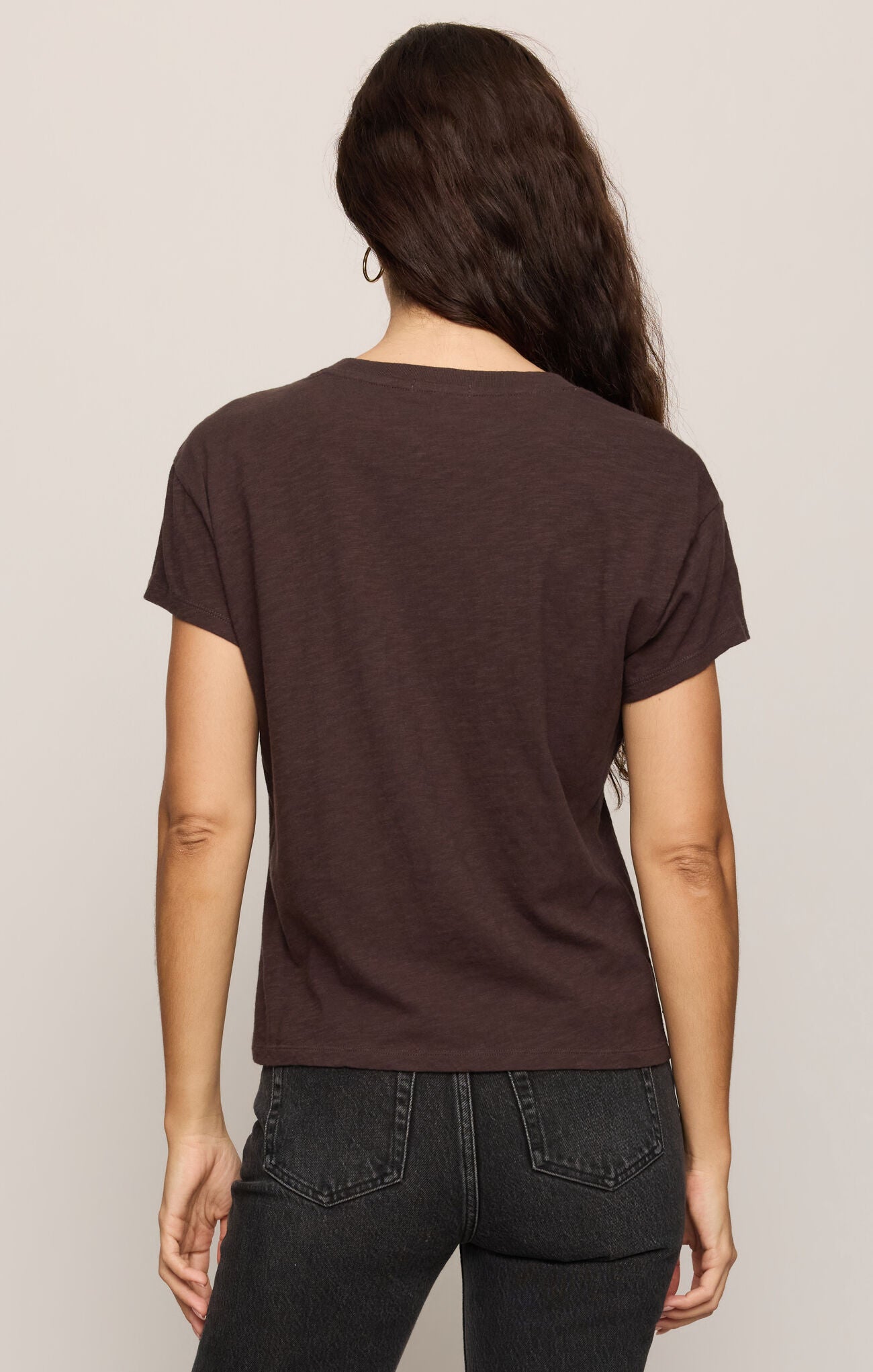 Person wearing a brown t-shirt and black pants on a plain background