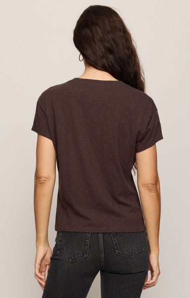 Person wearing a brown t-shirt and black pants on a plain background