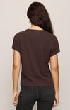 Person wearing a brown t-shirt and black pants on a plain background