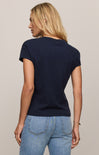 Woman wearing a navy blue t-shirt and light blue jeans on a plain background