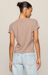 Woman wearing a brown t-shirt and light blue jeans against a beige background