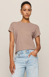 Woman wearing a brown t-shirt and light blue jeans against a beige background