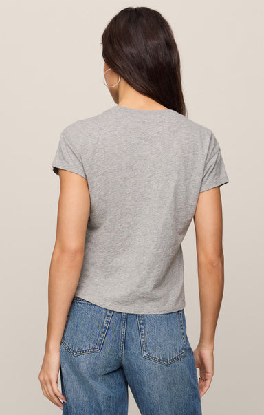 Person wearing a gray t-shirt and blue jeans on a beige background