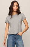 Woman wearing a gray t-shirt and blue jeans against a beige background
