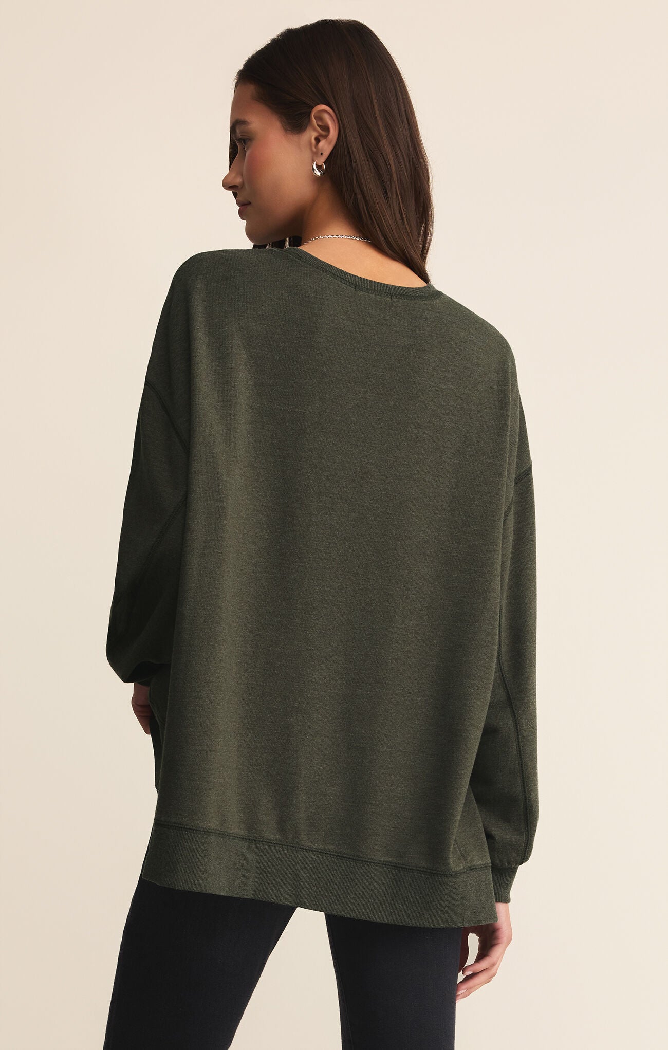 Person wearing a green sweater from behind on a beige background