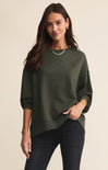 Woman wearing a green sweater against a beige background