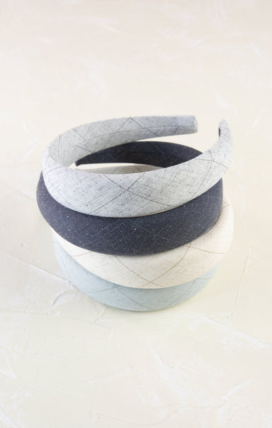 Two quilted headbands, one gray and one white, on a light beige background.