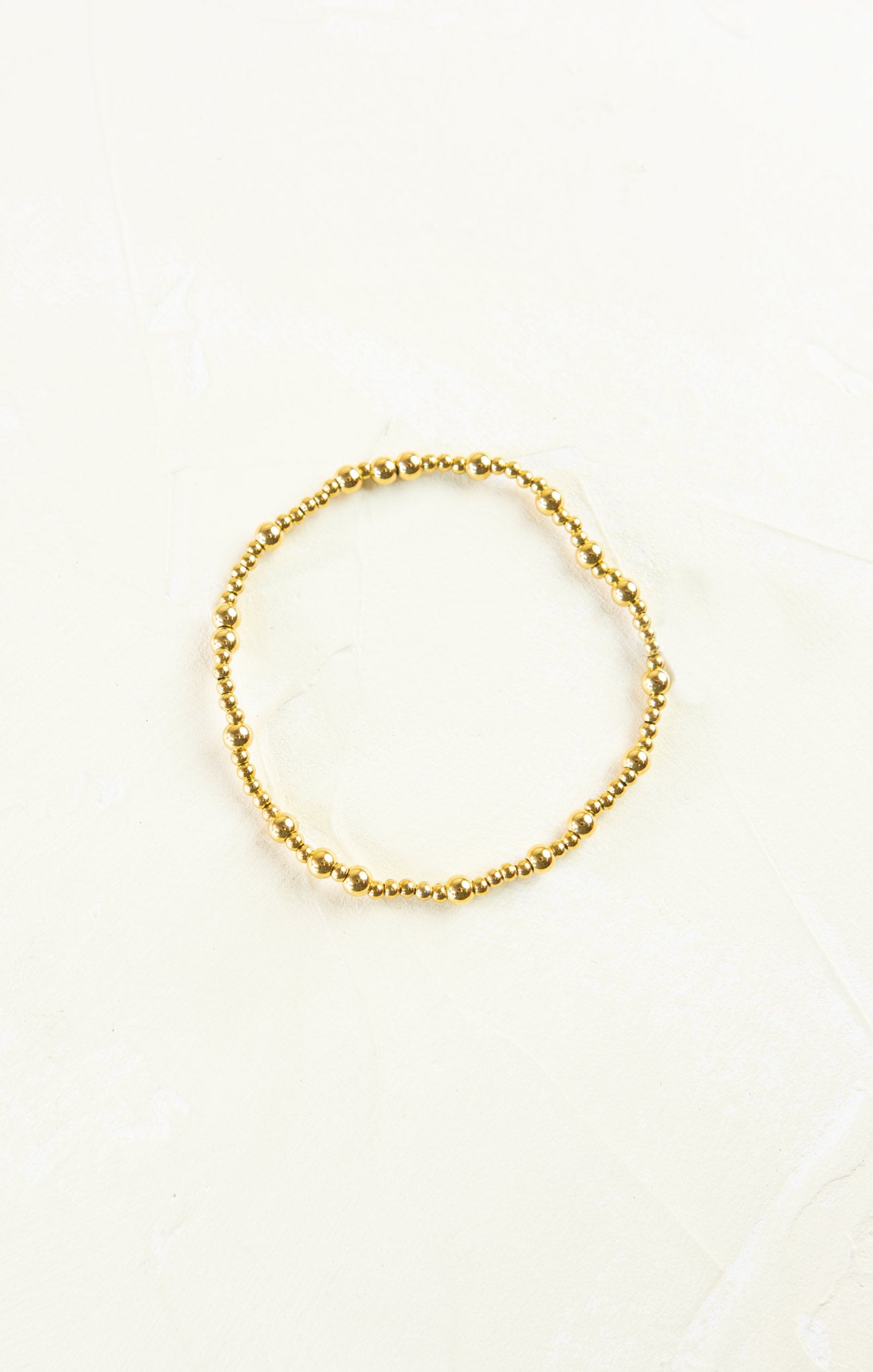 Gold beaded bracelet on a white background