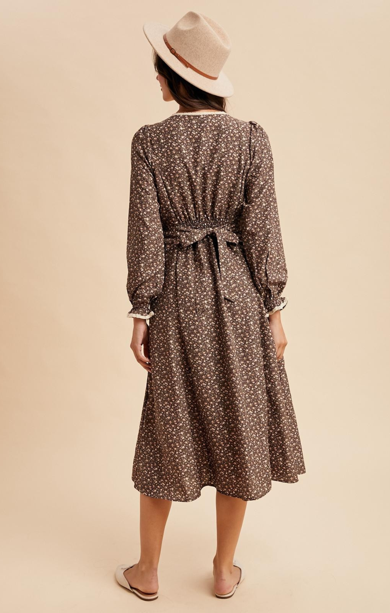 Woman wearing a patterned dress and hat on a beige background