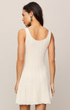 Woman wearing a white sleeveless dress against a plain background