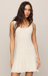Woman wearing a white sleeveless dress against a plain background