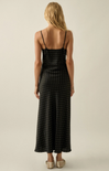 Woman wearing a black polka dot dress on a beige background