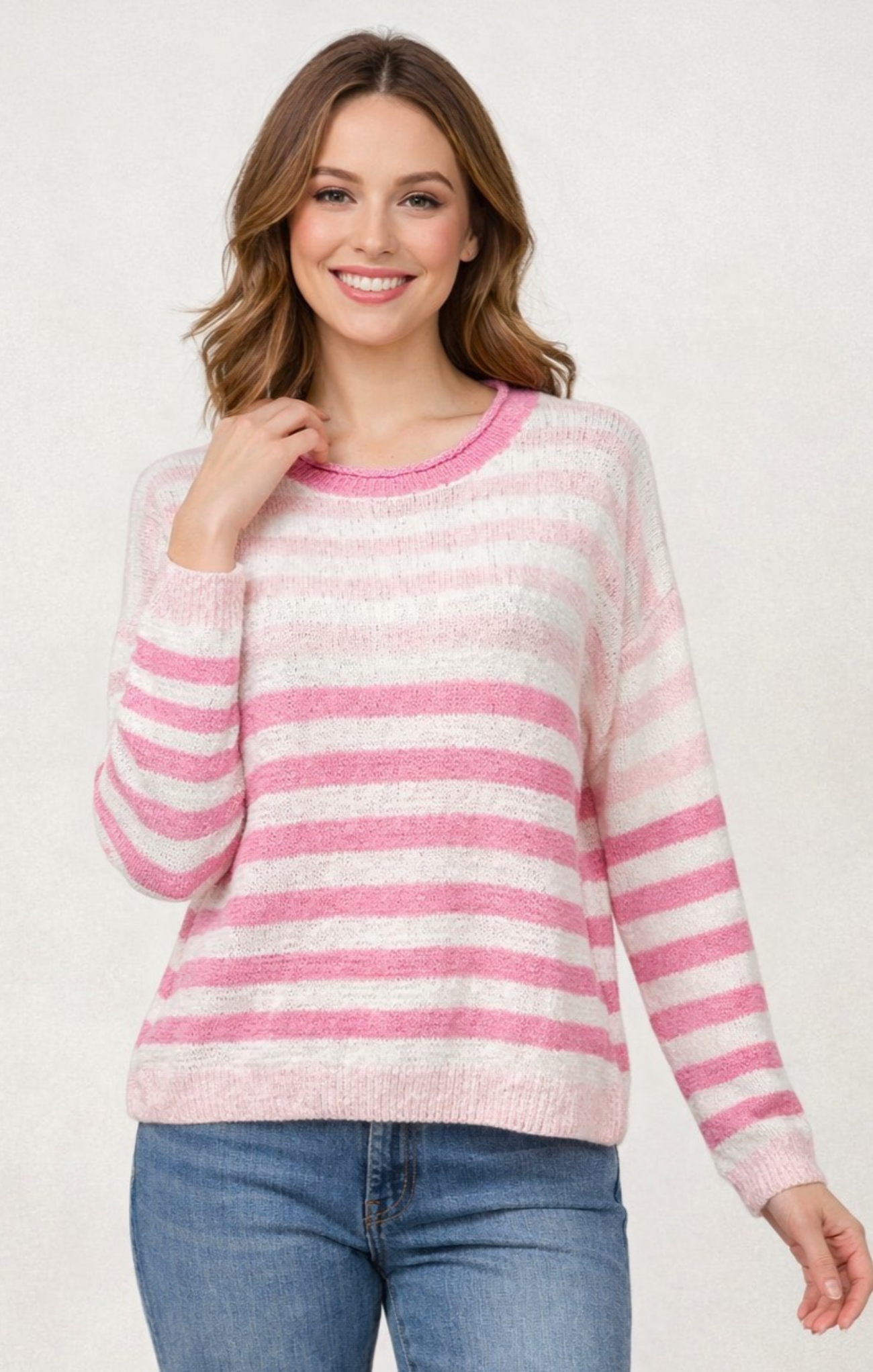 Woman wearing a pink and white striped sweater with blue jeans on a white background