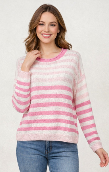 Woman wearing a pink and white striped sweater with blue jeans on a white background