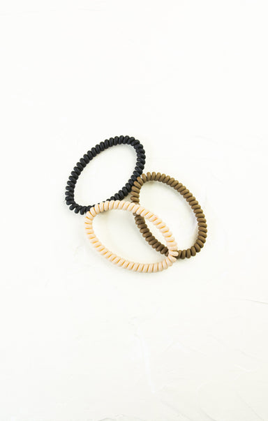 Three beaded hair ties in black, beige, and brown on a white background