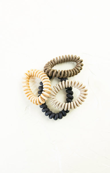 Set of four hair ties in beige, brown, black, and white on a white background