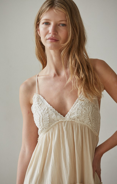 Woman wearing a beige lace nightgown against a plain background