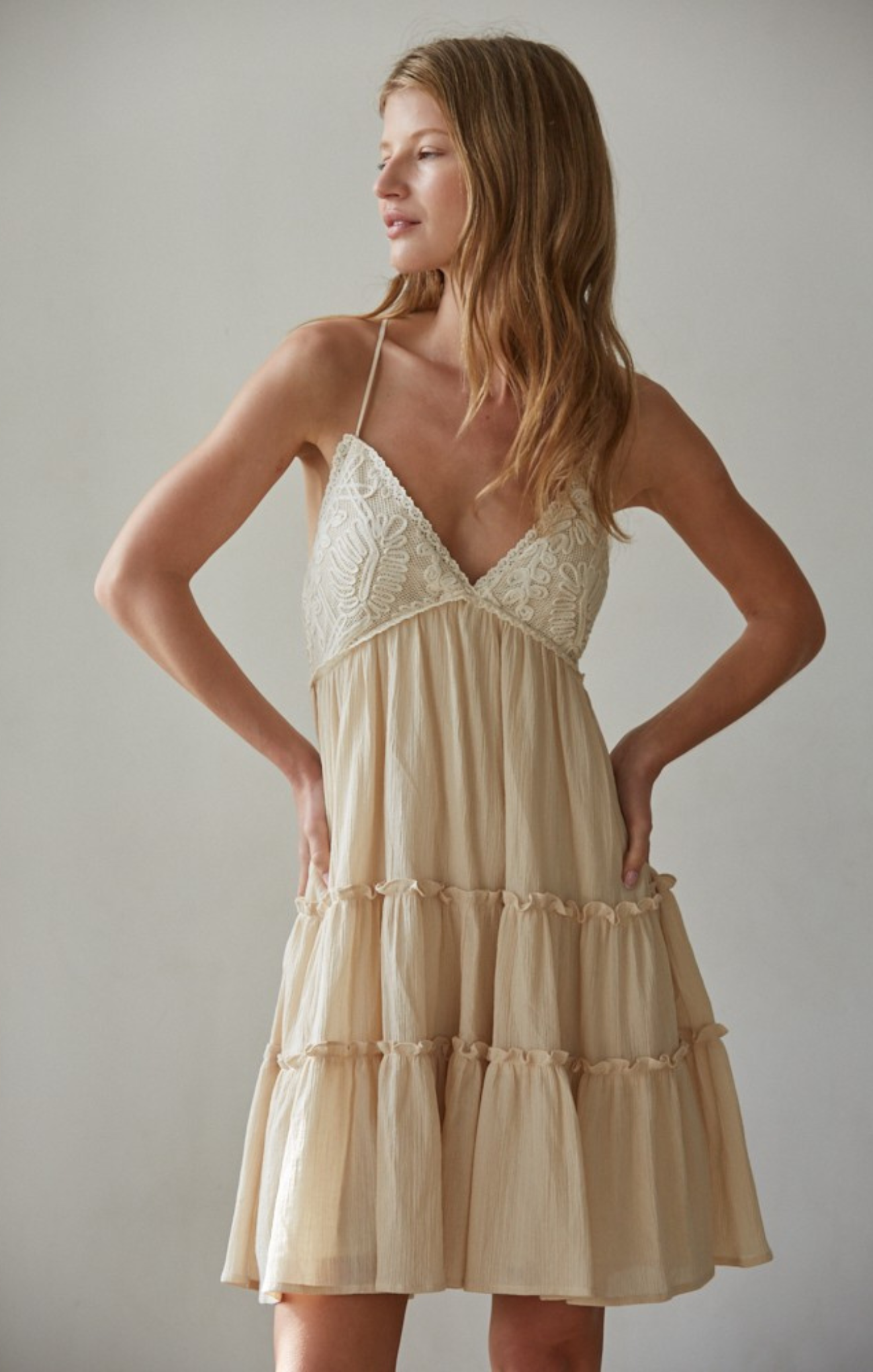 Woman wearing a beige dress against a plain background