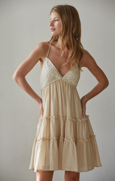 Woman wearing a beige dress against a plain background