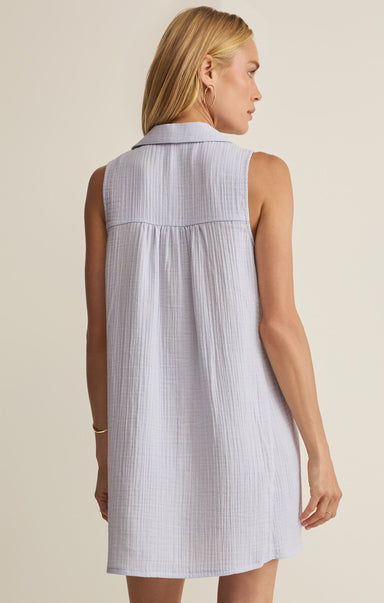 Woman wearing a sleeveless checkered dress against a neutral background