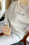 Person wearing a gray hoodie with 'niantic' branding, holding an iced coffee.