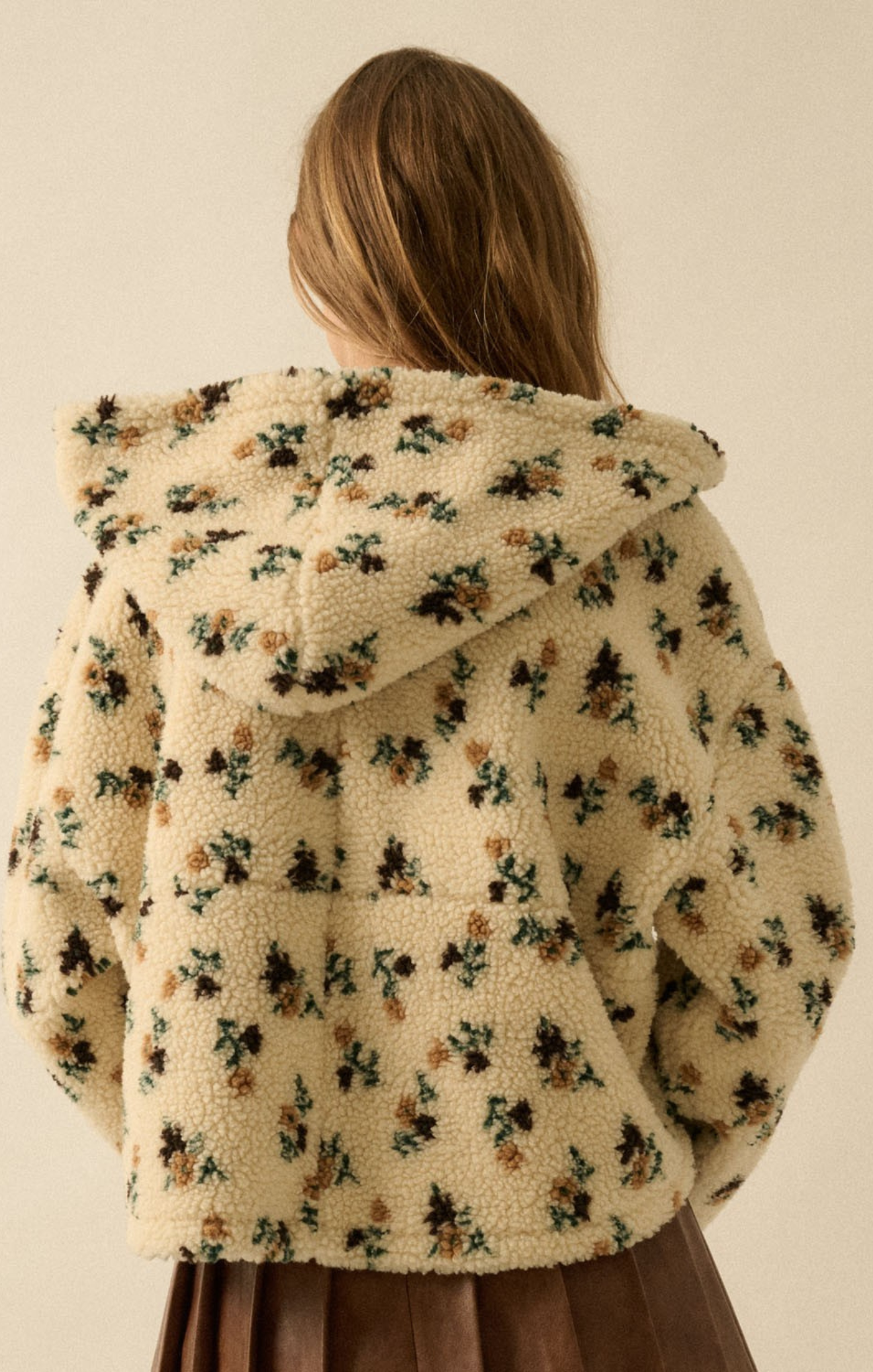 Floral-patterned fleece jacket worn by a person on a beige background