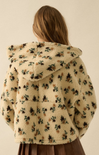 Floral-patterned fleece jacket worn by a person on a beige background