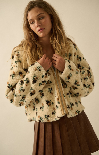 Woman wearing a floral-patterned beige jacket against a plain background