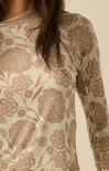 Close-up of a long-sleeve top with a beige and brown floral jacquard pattern, worn by a model.
