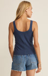 Woman wearing a navy tank top and denim shorts on a beige background