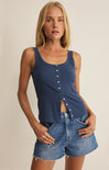 Woman wearing a blue tank top and denim shorts on a beige background