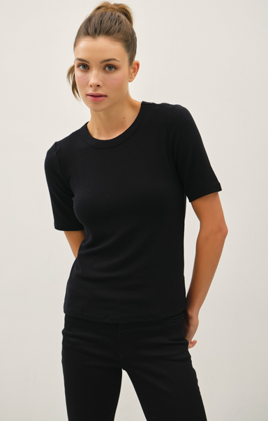 Woman wearing a black t-shirt and pants against a plain background