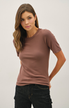 Woman wearing a brown t-shirt and black pants against a white background