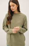 Woman wearing an olive green sweater against a white background