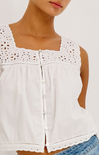 White sleeveless top with lace details worn by a person on a white background