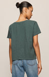 Person wearing a green t-shirt and blue jeans on a beige background