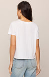 Person wearing a white t-shirt and light blue jeans on a beige background