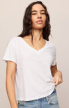 Woman wearing a plain white t-shirt and blue jeans against a beige background