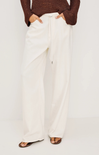Person wearing white pants and a brown top on a plain background