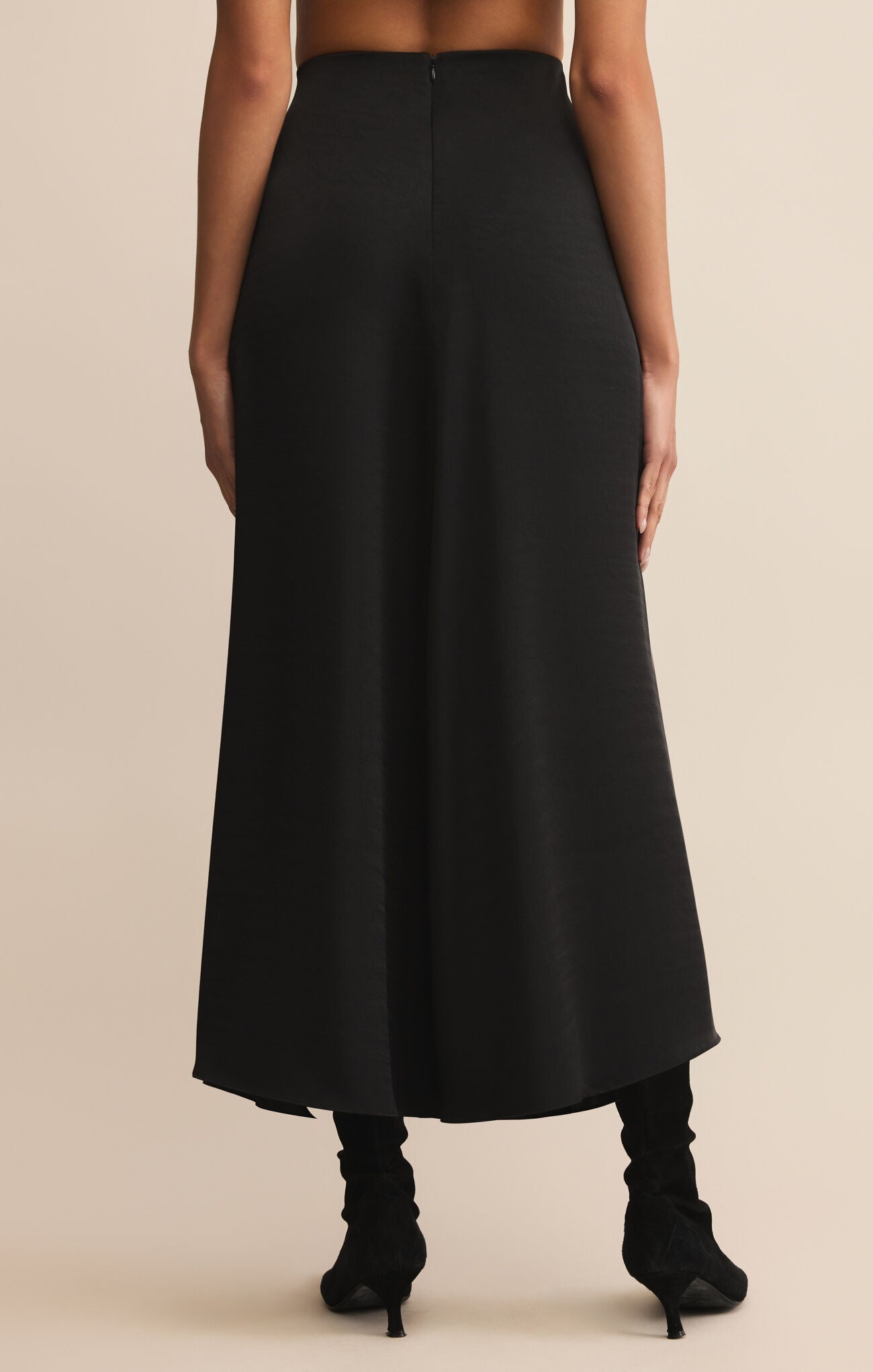 Black skirt worn by a person on a beige background