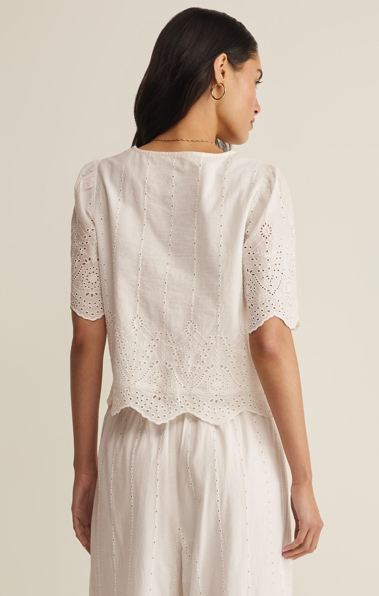 Woman wearing a white lace top and skirt set on a plain background