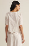 Woman wearing a white lace top and skirt set on a plain background