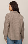 Woman wearing a brown checkered shirt and blue jeans on a beige background