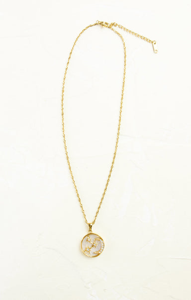 Gold necklace with a circular pendant on a white background