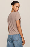 Woman wearing a beige t-shirt and blue jeans against a neutral background