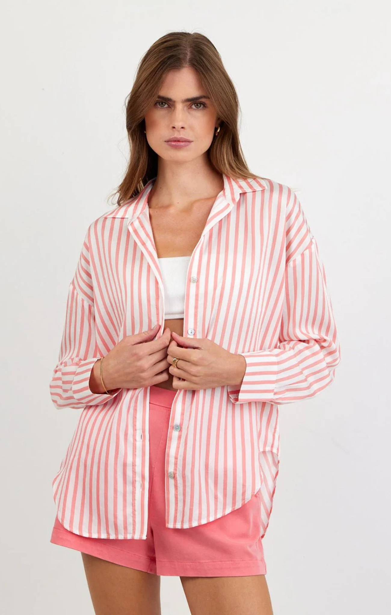 Woman wearing a pink and white striped shirt with matching shorts on a white background