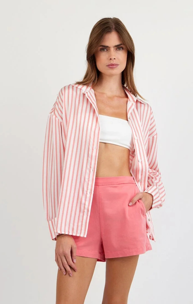 Woman wearing a pink and white striped shirt and pink shorts on a white background