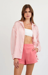 Woman wearing a pink and white striped shirt and pink shorts on a white background